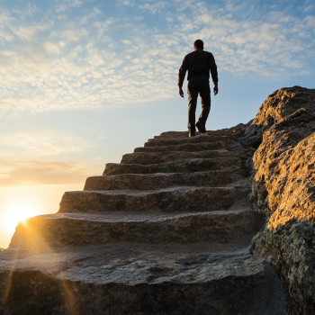 Mann steigt Steinstufen hoch während die Sonne hinter der Treppe aufgeht